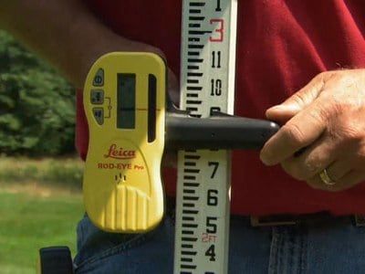 Landscaper using a Level to ensure Proper Grading