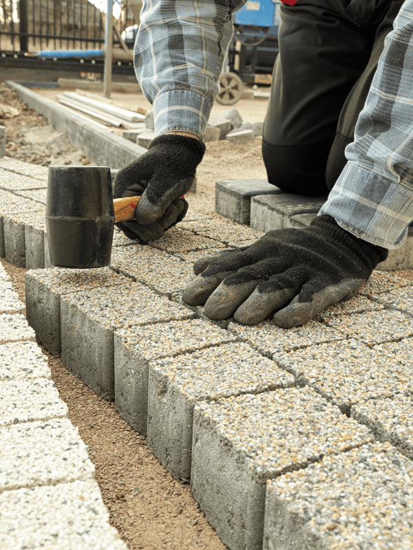 Close up image of landscaper installing gray pathway pavers in Helotes, TX